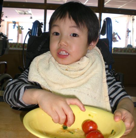 Ein kleines taiwanisches Mädchen isst Tomaten.